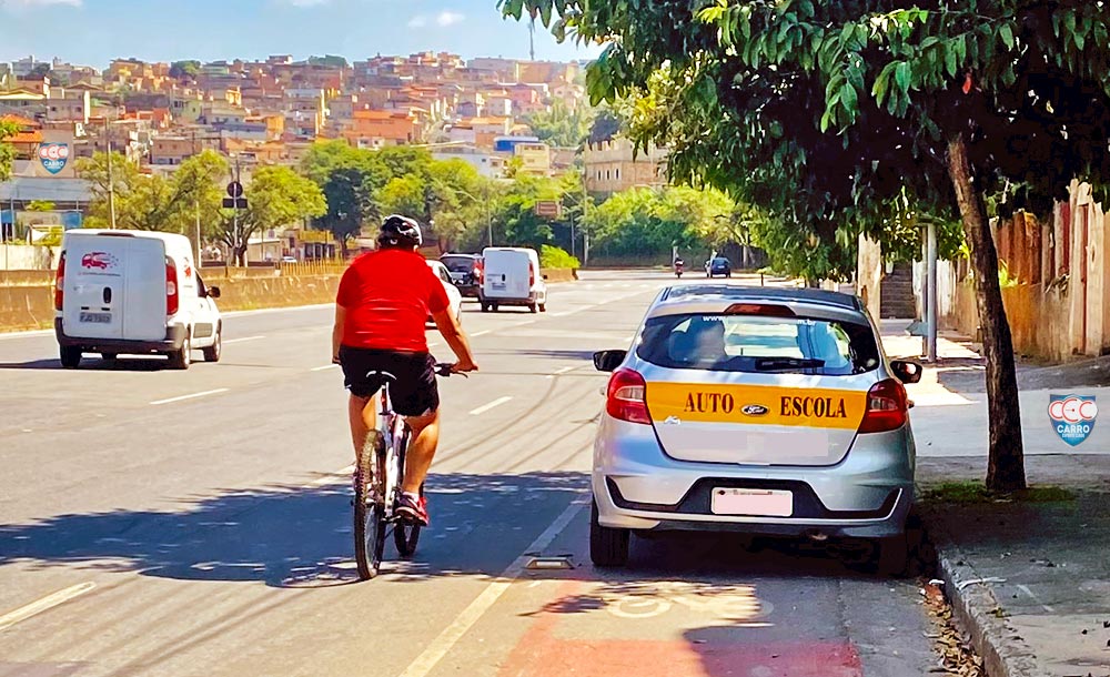 Flagrante de carro de autoescola parado na ciclofaixa, prejudicando ciclista: prática agora é infração de trânsito